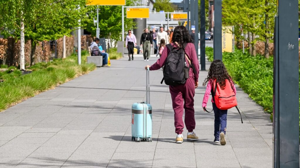 Mother and daughter walking with luggage outside the airport