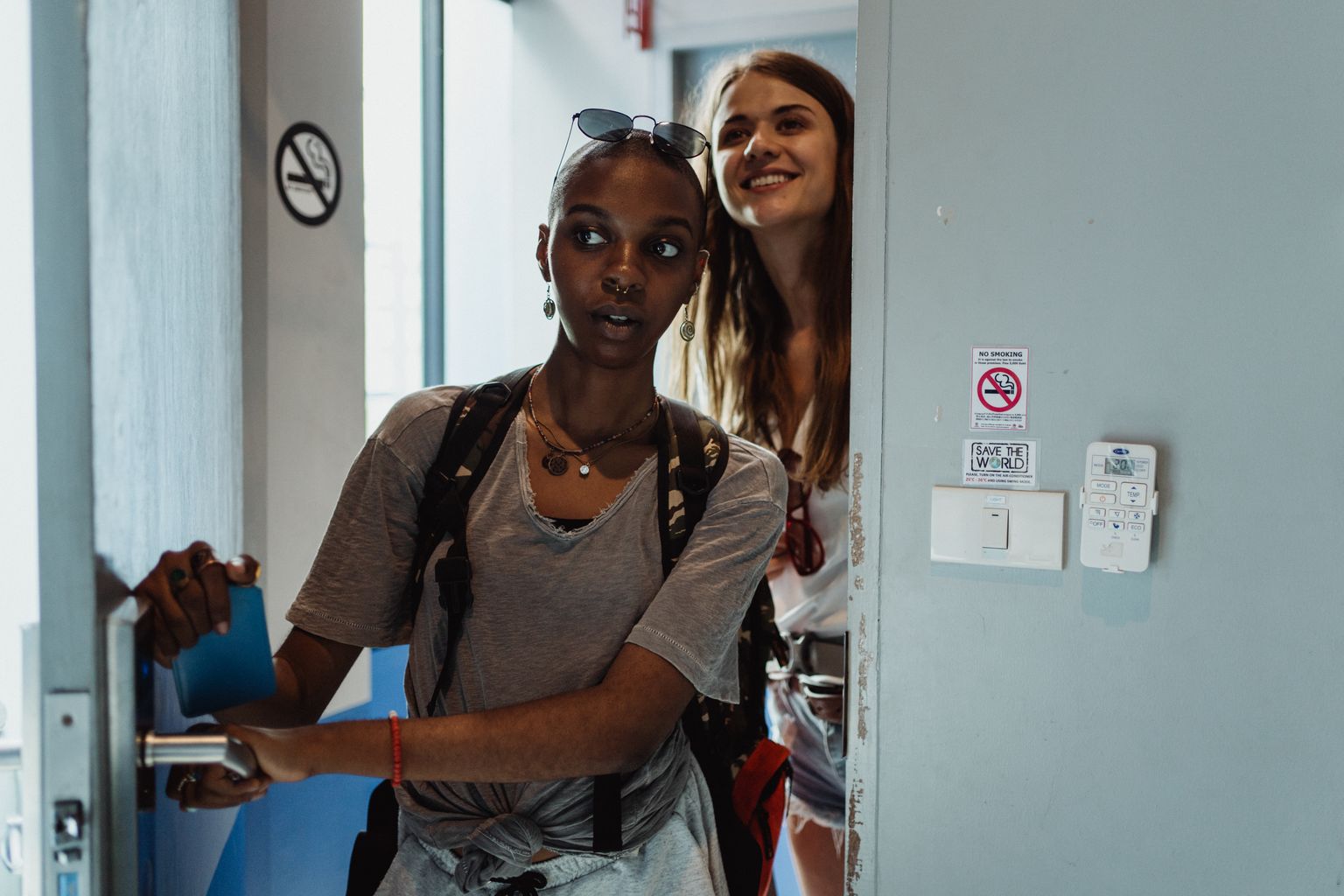 Two young travelers with backpacks entering a hostel room, a hotel alternative for 18 year olds