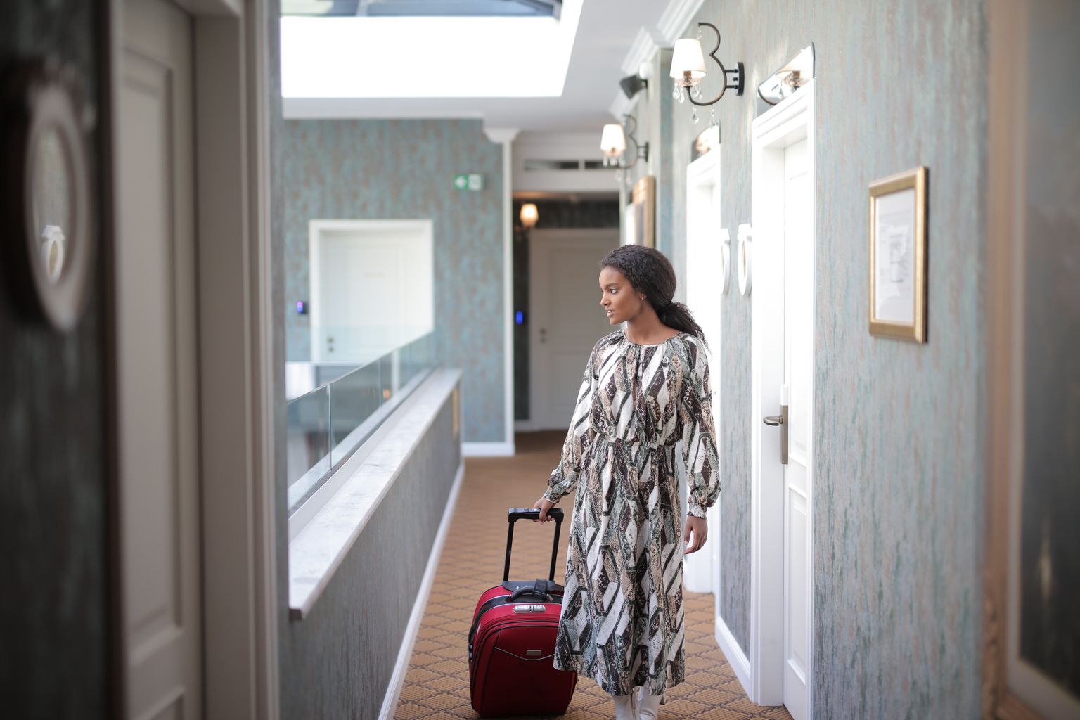 Traveler with luggage in a hotel corridor after choosing which OTA to book