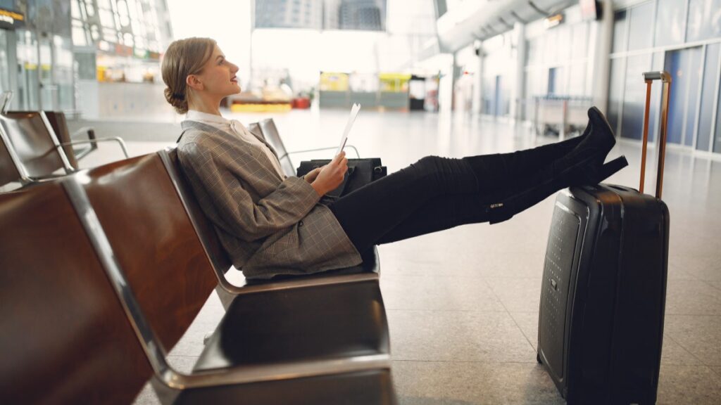 Traveler waiting at the airport checking flight prices on her phone